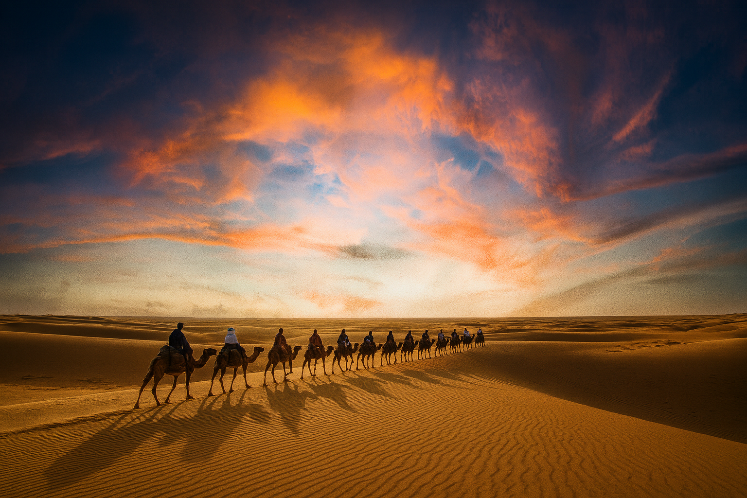 Caravana de camellos atravesando las dunas del Sahara al atardecer – Marruecos