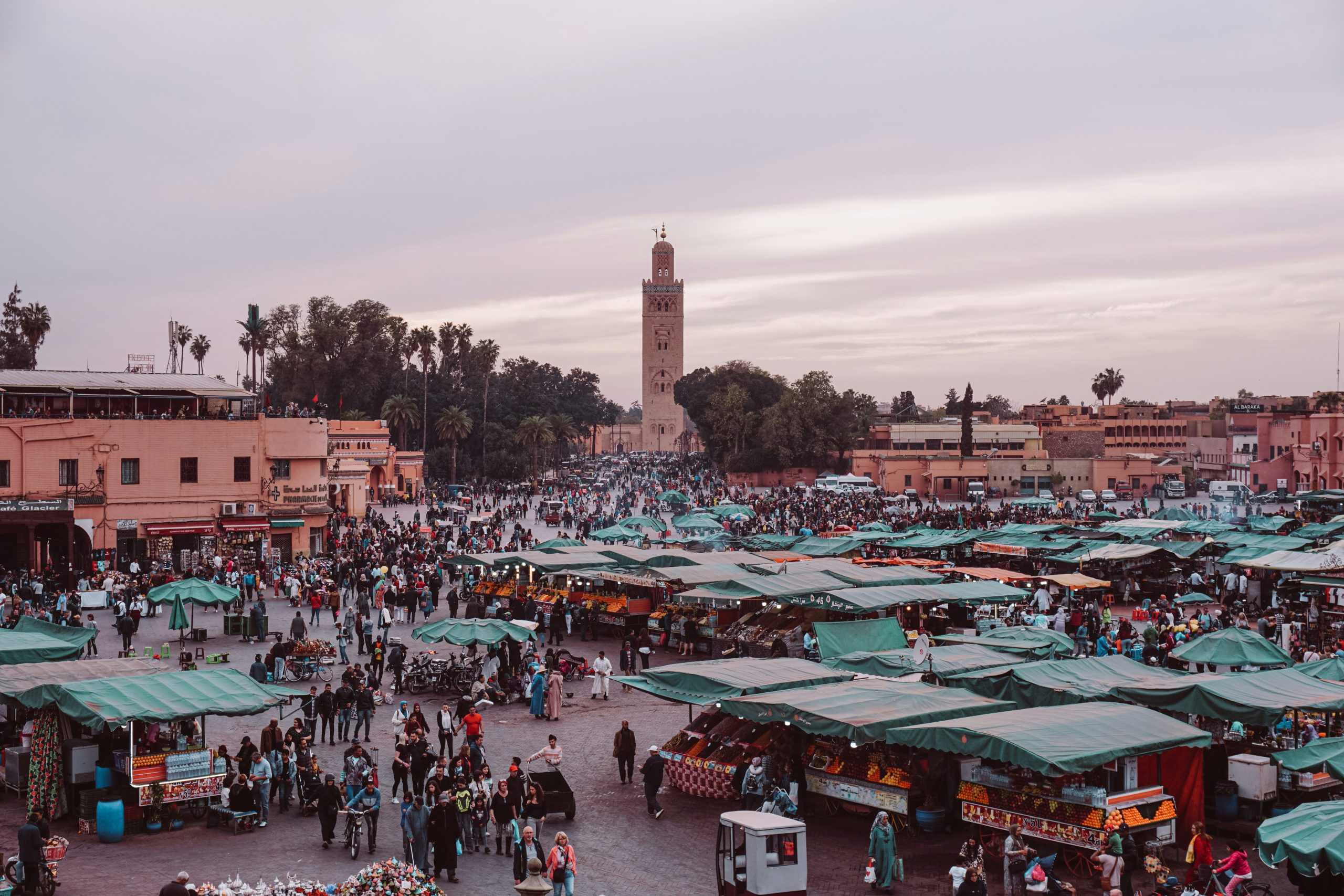 Plaza Jemaa el-Fna en Marrakech al atardecer con mercado y mezquita Koutoubia al fondo